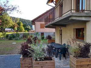 een terras met een tafel en stoelen voor een huis bij Gîte les Eglantines Rez-de-Jardin in Gérardmer