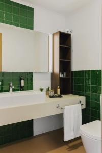 a bathroom with a sink and a toilet and green tiles at Hotel Ponta Delgada in Ponta Delgada