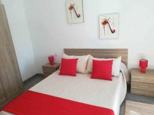 um quarto com uma cama grande e almofadas vermelhas em Apartamentos Harizan em Agaete