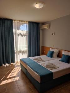 a bedroom with a large bed with blue pillows at Аурелия Бей in Ravda