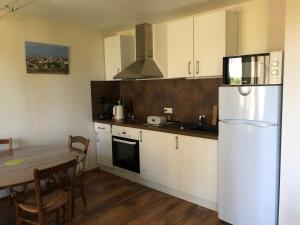 kuchnia z białą lodówką i stołem w obiekcie T3 LUC-LA-PRIMAUBE chez Monique 2 nuits minimum w mieście Luc