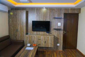 ein Wohnzimmer mit einem Sofa und einem TV an der Wand in der Unterkunft Hotel Airport Deepshree in Kathmandu
