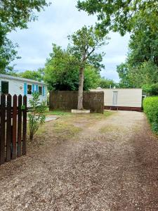 a home with a fence and a tree at Charmant bungalow à Saint-Pierre-d'Oléron - Jardin privé in Saint-Pierre-dʼOléron