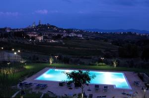 een zwembad 's nachts met uitzicht op de stad bij Villa Ducci in San Gimignano