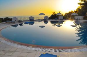 a large swimming pool with a sunset in the background at Apartments Maria with Amazing Pool - Agios Gordios Beach in Agios Gordios