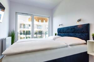 a white bedroom with two beds and a window at VacationClub - Let’s Sea Baltic Park C79 in Gąski