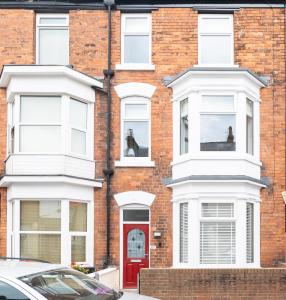 un edificio de ladrillo rojo con una puerta roja y un caballo en la ventana en Scarborough Stays - Trafalgar Lodge - 4 bedroomed house - Free Parking, en Scarborough