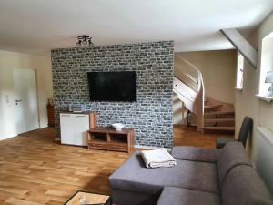 a living room with a tv on a brick wall at Ferienwohnung Am Bahnhof in Hasselfelde