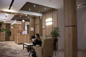 a woman sitting in a chair in a lobby at Lotus Hotel Chisinau in Chişinău