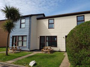 a house with two picnic tables in front of it at Perran View Holiday Park in St. Agnes