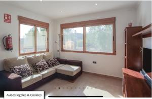 a living room with a couch and two windows at Apartamento Sierra Espuña in Alhama de Murcia