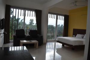 a bedroom with a bed and a couch and chairs at Grand Suites Yelahanka in Bangalore