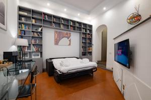 a room with a bed and a tv and bookshelves at Roman Forum Apartment - The Heart of Rome in Rome