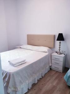 a bedroom with a bed with white sheets and a lamp at Premier Apartments in Valencia