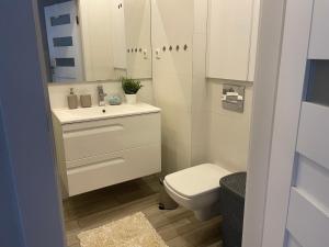 a bathroom with a white sink and a toilet at Apartament na Mazowieckiej in Kołobrzeg