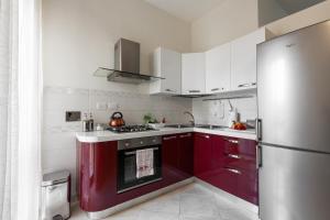 een keuken met rode kasten en een roestvrijstalen koelkast bij Casa Lucia in Lecce