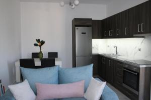 a living room with a blue couch and a kitchen at Drebos Apartments in Lazaráta