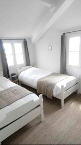 two beds in a room with two windows at Île de Ré - T3 avec sublime vue mer - 80m2 - 4 à 6 pers in Saint-Martin-de-Ré