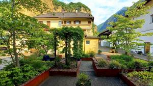 a building with a courtyard with plants and trees at Hotel Garni Grüner Baum (Albero Verde) in Laives