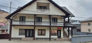 a large white house with a balcony on a street at Pensiunea Cheile Bicazului in Bicaz Chei