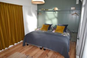 een slaapkamer met een bed met blauwe en gele kussens bij Huisje onder de Linden in Munnekeburen