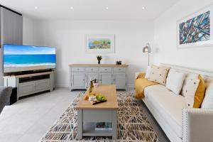a living room with a white couch and a tv at Out to Sea, 8 Grand Banks in Teignmouth
