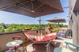 un balcón con hamaca, sillas y mesas en Lorraine Hôtel Nancy Ouest - Laxou, en Nancy