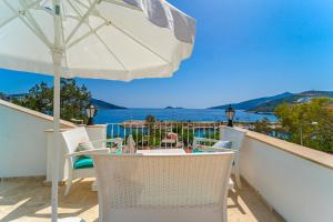 a table and chairs on a balcony with an umbrella at Pier Rooms & Pansiyon in Kalkan