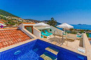 a villa with a swimming pool and an umbrella at Pier Rooms & Pansiyon in Kalkan