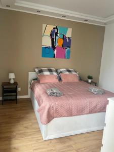 a bedroom with a bed with pink sheets and a painting at Apartament na Mazowieckiej in Kołobrzeg