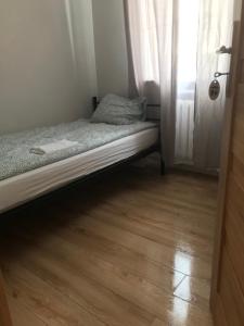 a small bed in a room with a wooden floor at Good Night in Warsaw