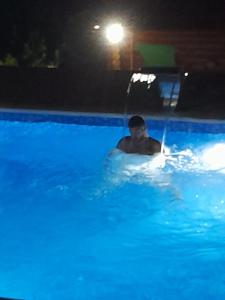 a man in a swimming pool at night at Apartmani Žuti Leptir in Vrdnik