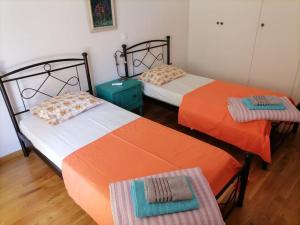 duas camas com lençóis laranja e branco num quarto em Athens Apartment em Atenas