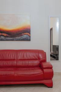 un sofá de cuero rojo en una sala de estar con una pintura en Casa Lucia, en Lecce