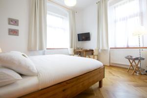 1 dormitorio con 1 cama con sábanas blancas y ventanas en Wellness Penzion U Muzea, en Liberec