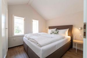 ein großes weißes Bett in einem Zimmer mit zwei Fenstern in der Unterkunft Villa Doctores - Remise 08 in Heringsdorf