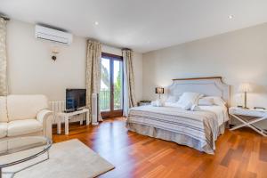 a bedroom with a bed and a chair and a television at Villa Cala Estancia Mercedes by PriorityVillas in Palma de Mallorca