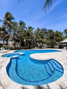 a swimming pool with blue water and palm trees at Hotel California Playa El Yaque in El Yaque