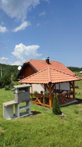 a gazebo with a roof on top of a field at Vikendica Studenac in Zlatibor