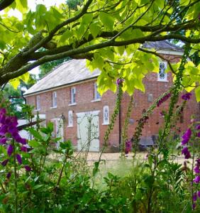 un viejo edificio de ladrillo con flores delante en The Georgian Coach House:New Forest with hot tub, en Fordingbridge