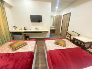 a hotel room with two beds and a desk at Hotel Sagar in Guwahati