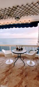 uma mesa e cadeiras num quarto com vista para o oceano em Aptartamentos Temáticos con balcón panorámico frente a la Playa em Santa Marta