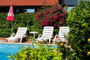 ソゾポルにあるApart-Hotel Onegin & Thermal Zoneのプールサイドの白い椅子3脚、テーブル、パラソル付