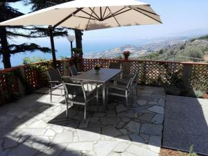 un patio con mesa, sillas y sombrilla en Tramonti e mare 2, en Cipressa
