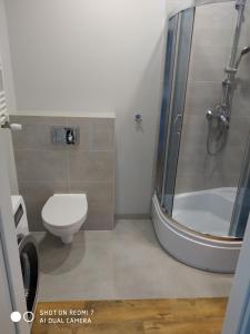 a bathroom with a shower and a toilet and a sink at Apartament4U - Olimpijskie Ogrody in Suwałki
