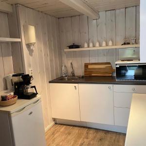 a kitchen with white cabinets and a sink and a microwave at Bryggerhus Og Leilighet in Kragerø