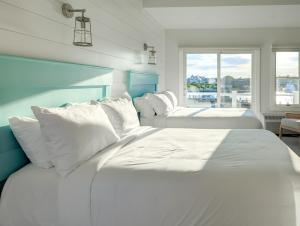 2 weiße Betten in einem Zimmer mit Fenster in der Unterkunft Falmouth Tides in Falmouth