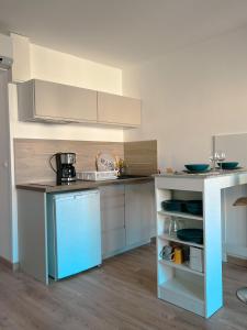 uma cozinha com armários brancos e um frigorífico azul em Studio Roncu em Calvi