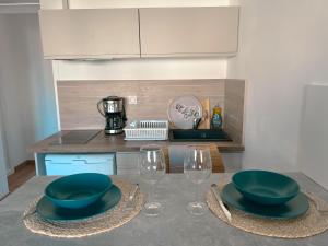 uma cozinha com dois pratos verdes e copos numa mesa em Studio Roncu em Calvi