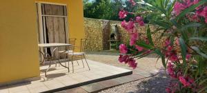 a patio with a table and chairs and pink flowers at Apartments Sunshine & Smile in Klimno